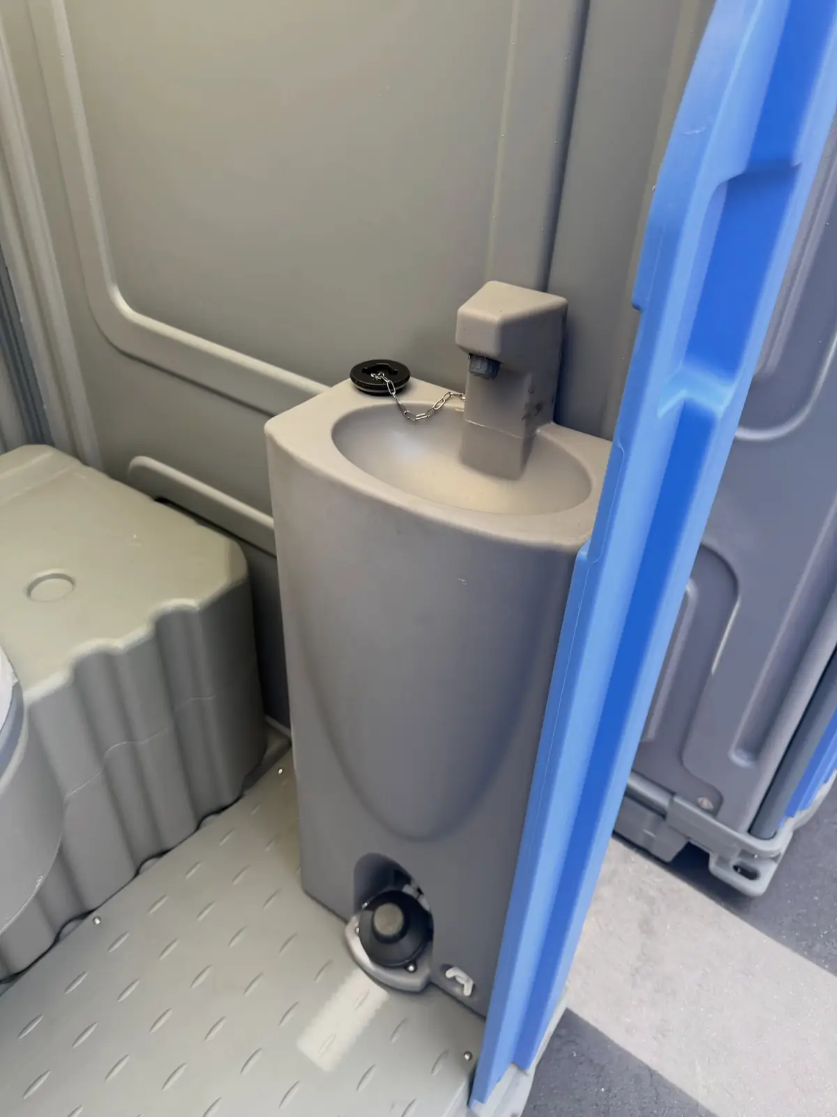 Inside a deluxe portable toilet with a foot-pump hand sink and soap dispenser
